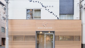 Exterior del hotel Sakura Cross, con un diseño moderno, que destaca por su fachada de madera y una entrada despejada.