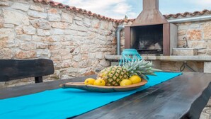 A stone wall with a tiled roof, a wooden bench, and a table with a blue mat. - Villa Lucia (Marcana)