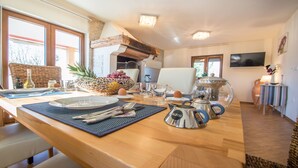 Un comedor con una mesa de madera dispuesta para el desayuno, incluyendo platos, cubiertos y un frutero.
