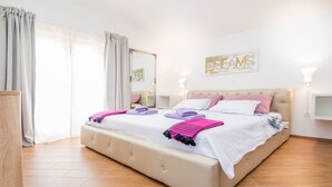 Un dormitorio con una cama grande, una mesita de noche, un espejo y una pared con un cartel.