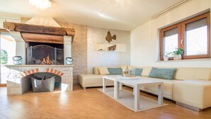 Una sala de estar con chimenea, un sofá, una mesita de centro y una ventana con plantas.