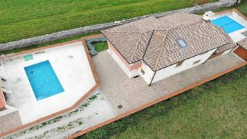 Propiedad residencial con piscina, terraza cubierta y muro de piedra.