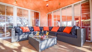 A modern living room with a sectional sofa, a glass coffee table, and large windows.