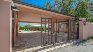 A gated entrance to a property with a pool and outdoor seating area. - Villa Duda (Vodnjan)