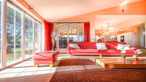 A modern living room with a red sofa, a matching ottoman, and a wooden coffee table.