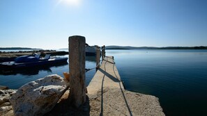 A pier leading to calm water with a boat docked nearby. - Holiday House Roses (Medulin)