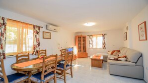A cozy living room with a sofa, a dining table with chairs, and a cabinet. - Holiday House Roses (Medulin)