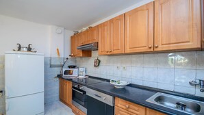 A kitchen with wooden cabinets, a black countertop, a white refrigerator, a Bosch dishwasher, and a microwave. - Holiday House Roses (Medulin)