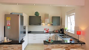 Una cocina moderna con refrigerador, armarios, pileta y ventana.