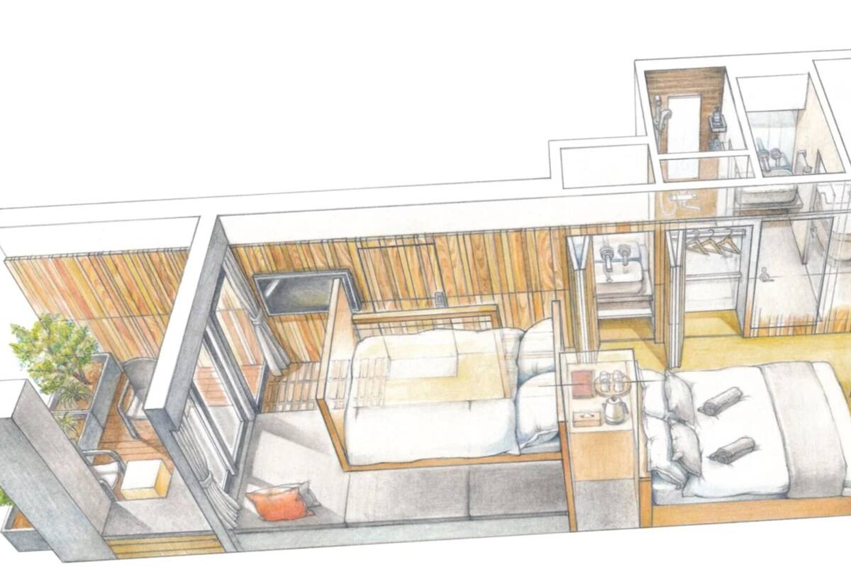 A modern hotel room with a large bed, a desk, a chair, and a small table. There is a window with curtains, a plant, and a view of the outside.