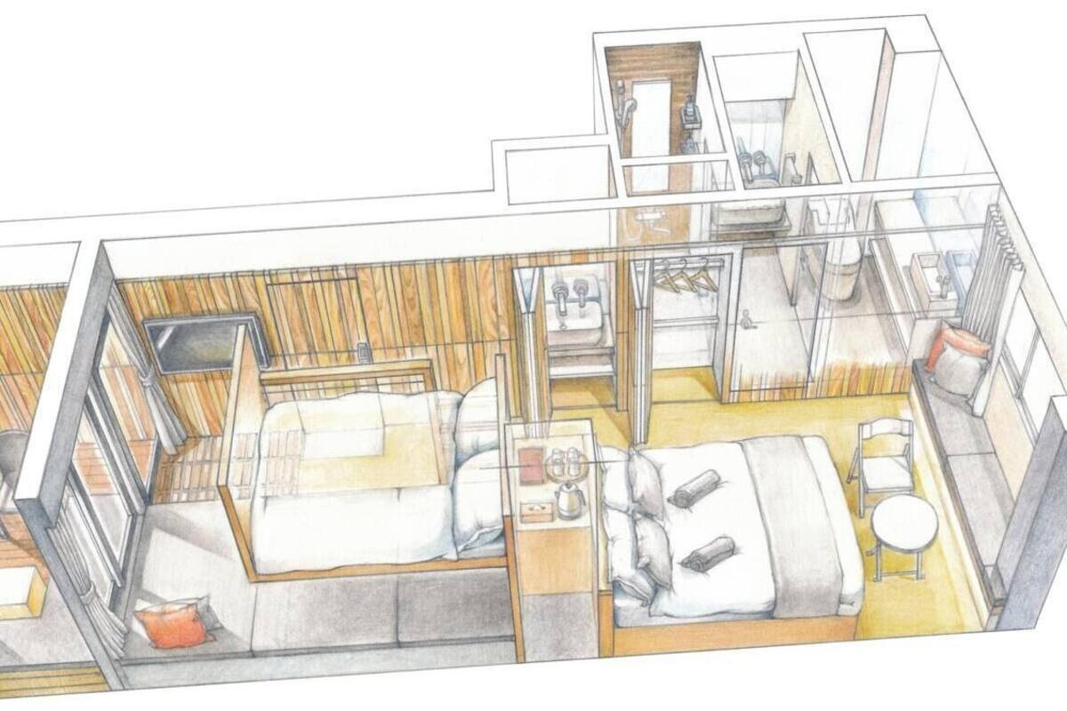A modern hotel room with a bed, bedside table, and a small seating area.