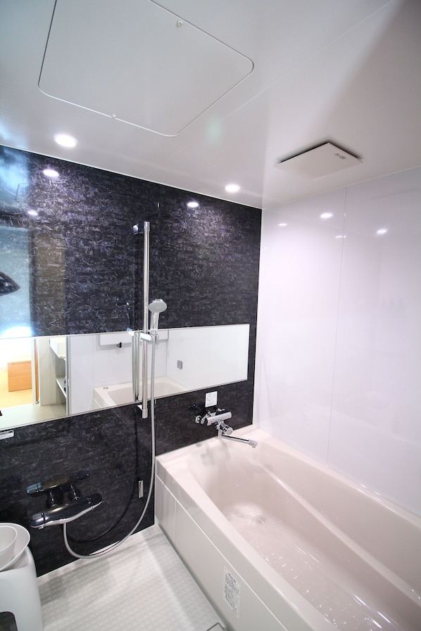 Un baño moderno con bañera, ducha y un espejo grande.
