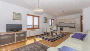 Un apartamento moderno con sala de estar, comedor, cocina y un amplio ventanal con vista al mar.