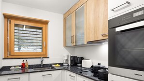 A modern kitchen with white cabinets, a black refrigerator, a coffee maker, and a toaster. - Silence by Interhome (Zermatt)