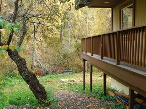 A wooden deck with a railing overlooking a forested area.