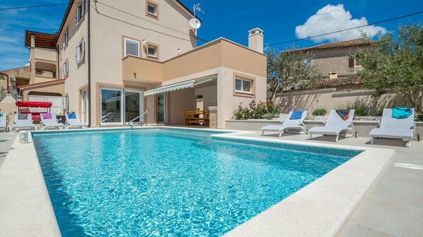A swimming pool with lounge chairs and a building with balconies. - Villa Grannys House (Medulin)