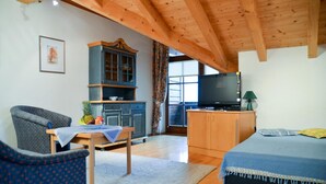A cozy room with a wooden ceiling, a bed, a TV, a cabinet, and a chair. - Hotel Restaurant Alpenhof (Uebersee)