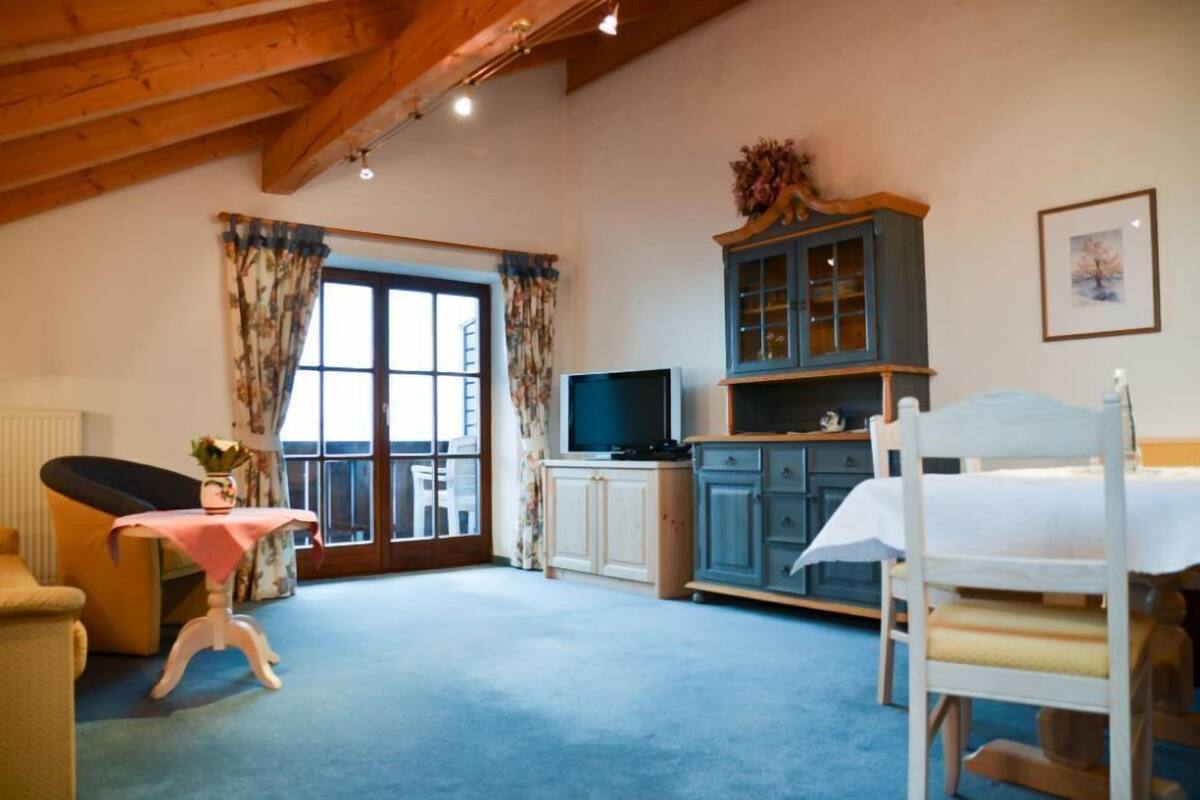 A bedroom with a bed, a television, a cabinet, and a window with curtains.