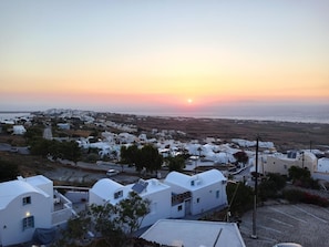 A coastal village with white buildings, a sunset, and a view of the sea. - Panorama View (Santorini)