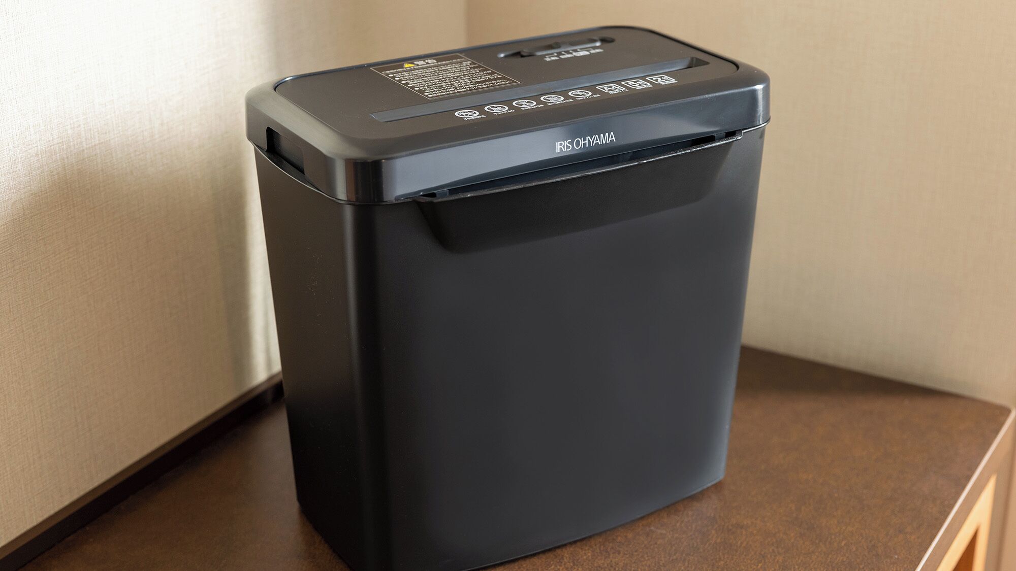 A black trash bin with the label "IRIS OHYAMA" on a wooden surface.