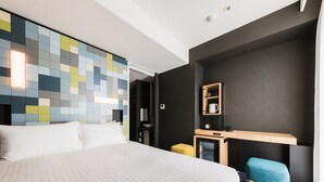 A modern hotel room with a large bed, a small desk, a mirror, and a colorful wall. - JR East Hotel Mets Premier Akihabara (Tokyo)