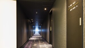 A long, narrow hallway with a patterned carpet, walls with directional signs, and a ceiling with recessed lighting. - JR East Hotel Mets Premier Akihabara (Tokyo)