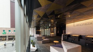 A modern lobby with geometric ceiling design, seating areas, and a reception desk. - JR East Hotel Mets Premier Akihabara (Tokyo)
