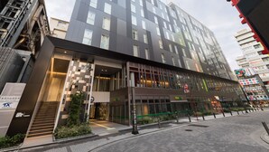 A modern hotel with a glass facade, multiple floors, and a prominent entrance with a staircase. - JR East Hotel Mets Premier Akihabara (Tokyo)