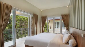 A bedroom with a large bed, sliding glass doors to a balcony, and a view of greenery.