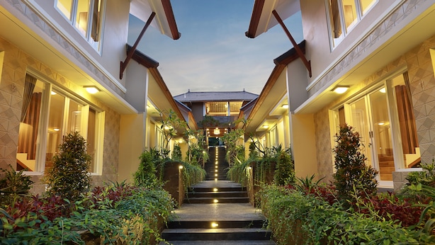 A staircase leading to a second-floor entrance, flanked by lush greenery and illuminated by warm lighting.