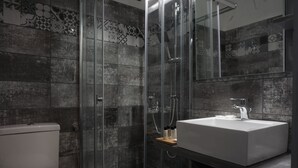 A modern bathroom with a glass-enclosed shower, a white sink, and a toilet. - Liprando (Paros)
