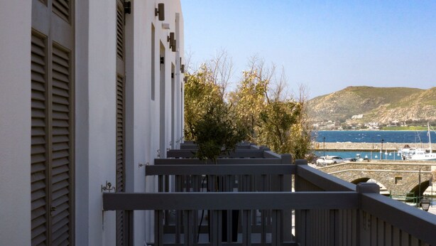 A balcony with a view of a coastal town, a stone wall, and a clear blue sky. - Liprando (Paros)