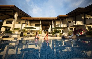 Una piscina al aire libre, sombrillas, sillones reclinables de piscina