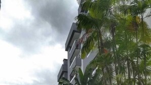 A modern multi-story building with balconies, surrounded by lush greenery and a curved water feature. - Beautiful new apartment! (Ubatuba)