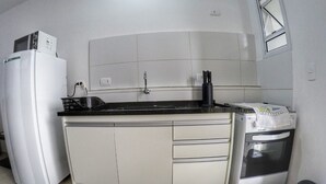A compact kitchen with a refrigerator, stove, and sink. - Beautiful new apartment! (Ubatuba)