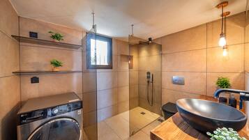 Ein modernes Badezimmer mit integriertem Waschbecken, einer Glasdusche und einem Holzbadezimmer-Möbel mit großem Waschbecken.