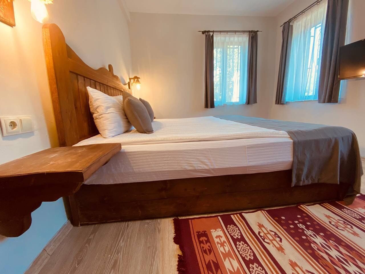 Une chambre à coucher avec un lit en bois, une table de chevet et un tapis à motifs.