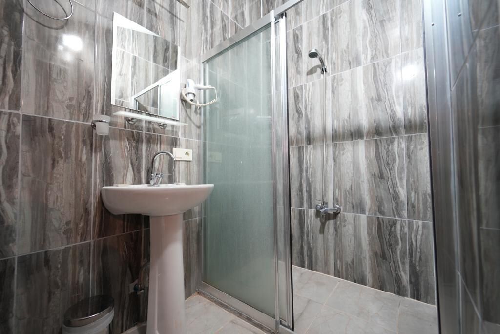 A bathroom with a sink, mirror, and shower.