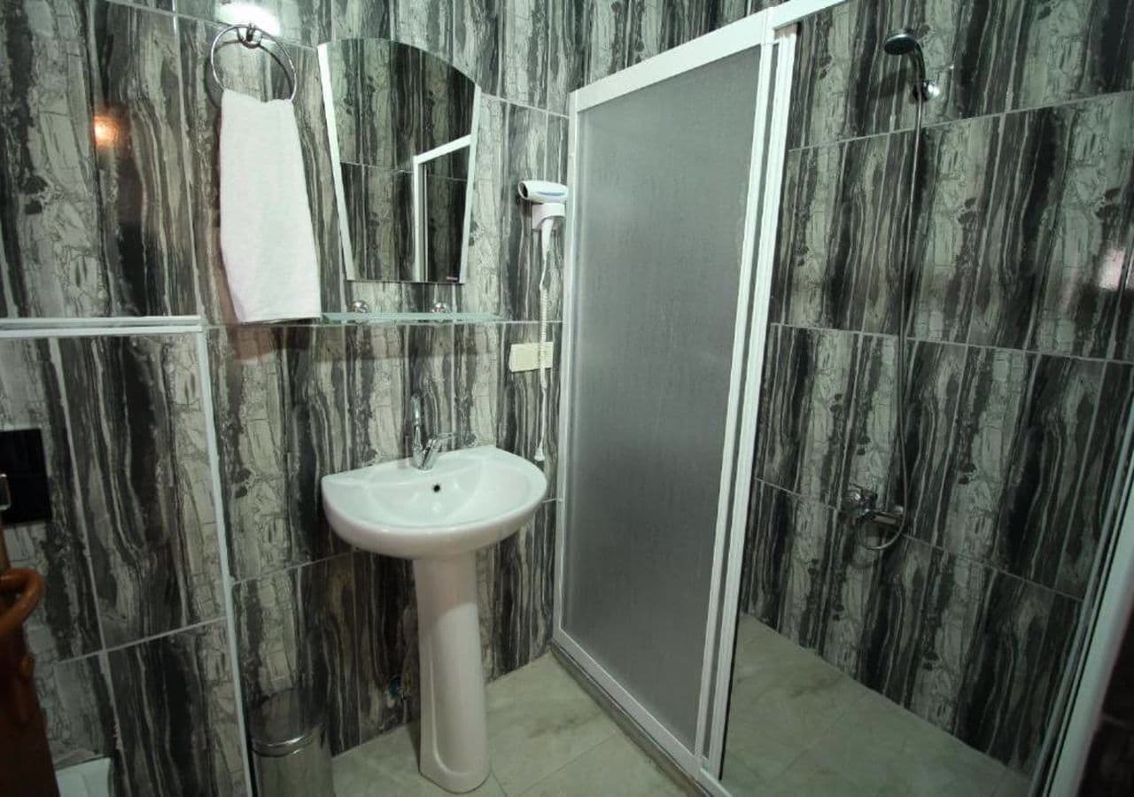 Ein Badezimmer mit Marmorfliesen, einem Standwaschbecken, einem Handtuchhalter und einer Duschkabine.