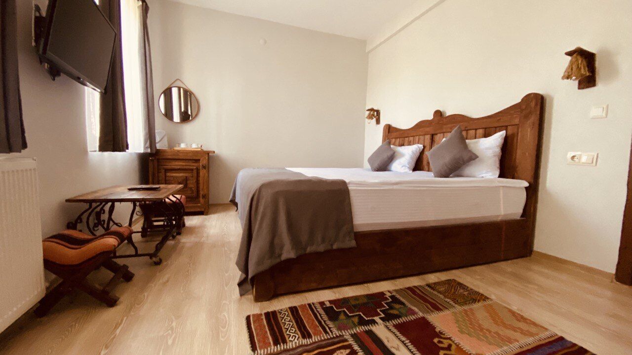 A bedroom with a bed, a desk, a chair, a TV, and a mirror.