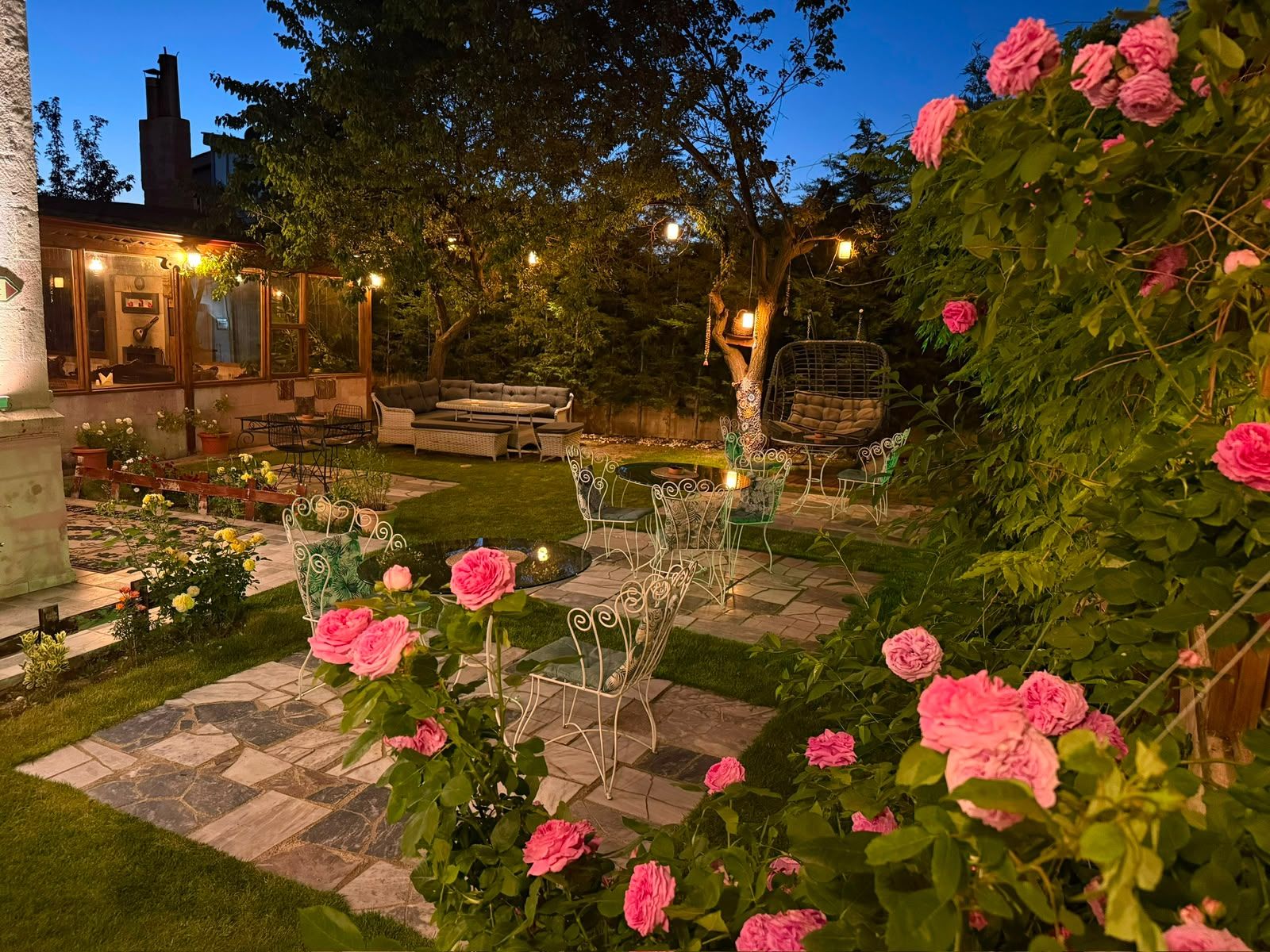 A garden with a seating area, a pond, and a variety of plants and flowers.