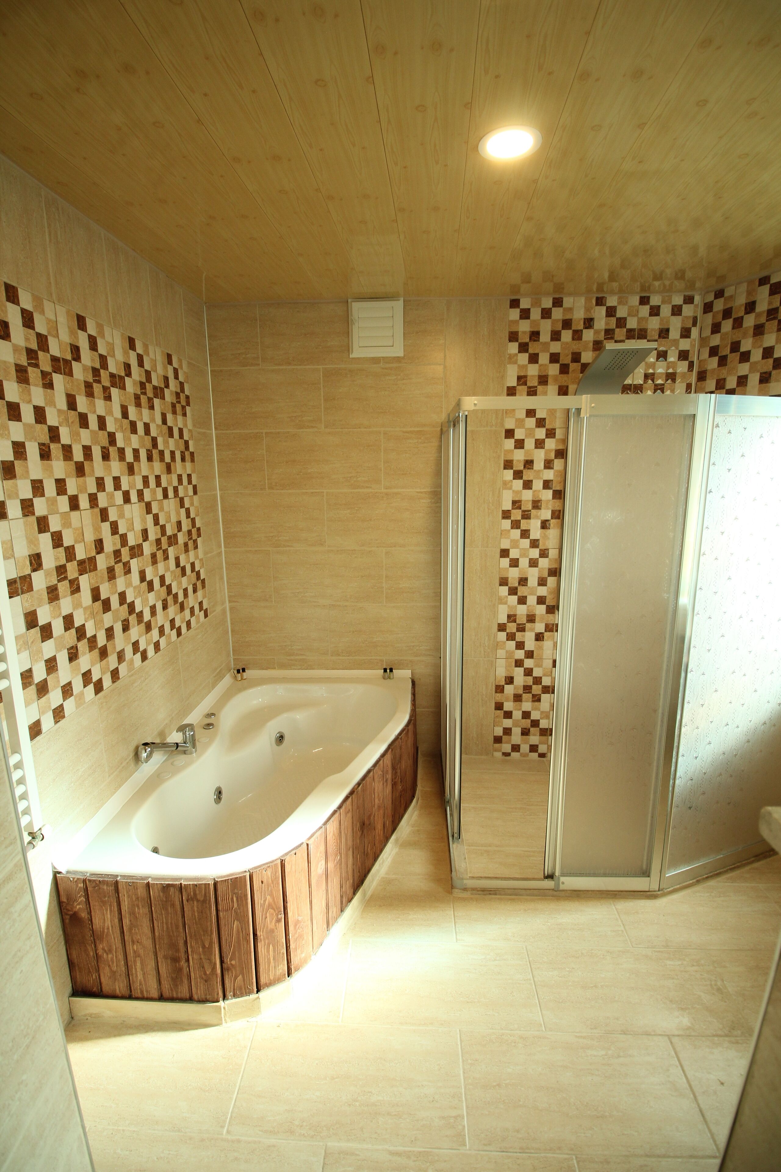 Ein modernes Badezimmer mit einer Holzbadewanne, einer Duschkabine aus Glas und gefliesten Wänden.