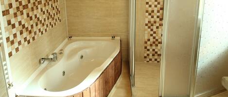 Ein modernes Badezimmer mit einer Holzbadewanne, einer Duschkabine aus Glas und gefliesten Wänden.