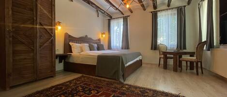 Ein Schlafzimmer mit Holzbalkendecke, einem Bett mit Kopfteil, einem Schreibtisch und einem Stuhl.