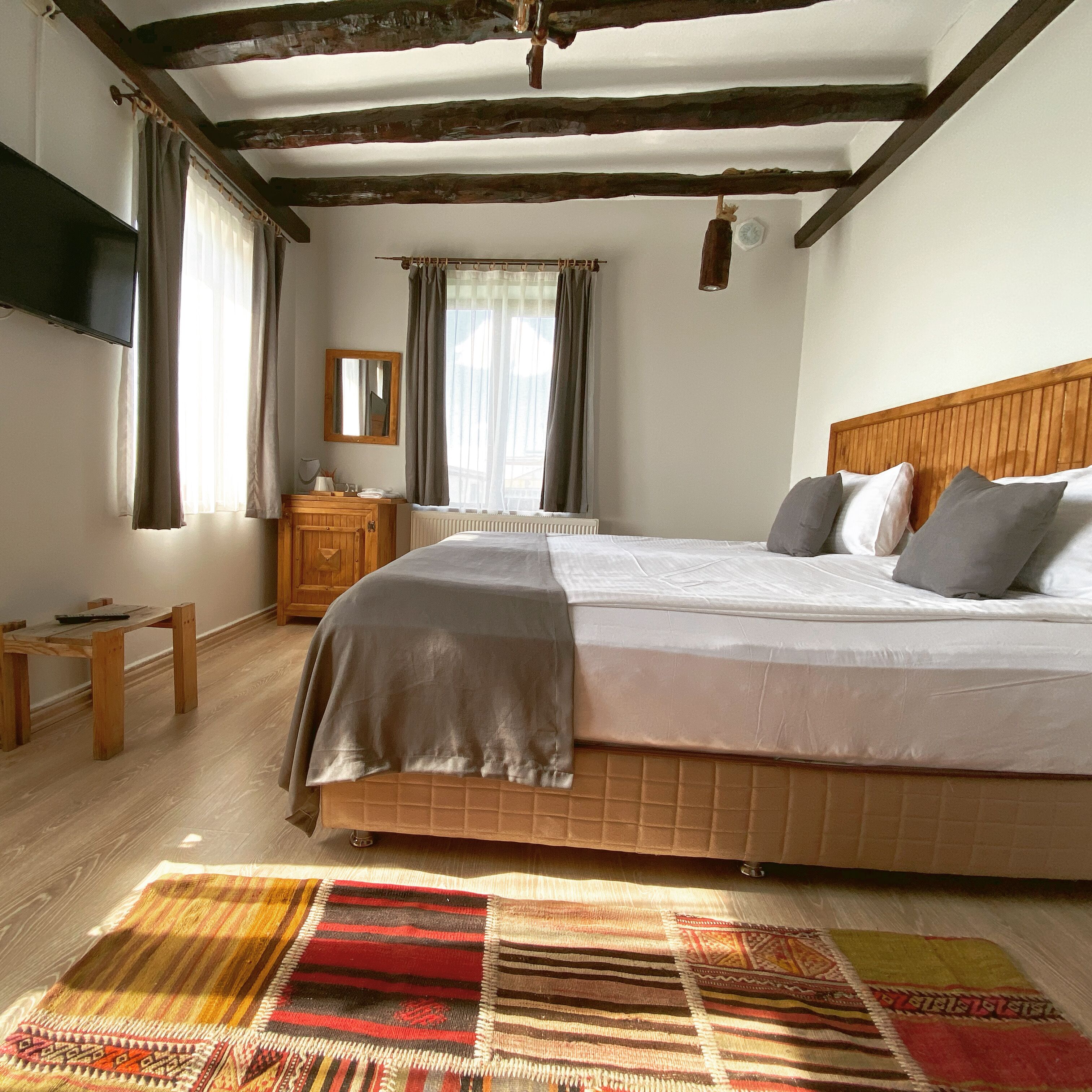 A bedroom with a wooden bed, a nightstand, a mirror, and a window with curtains.