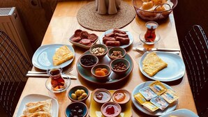 A table set with various dishes including pastries, meats, and vegetables, indicating a meal setup. - Kapadokya Konak (Nevsehir)