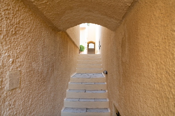 A narrow, stone staircase leading to an arched doorway, surrounded by textured walls.