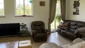 Un salon comprenant un canapé, des fauteuils, une table basse, un t éléviseur et un ventilateur de plafond.