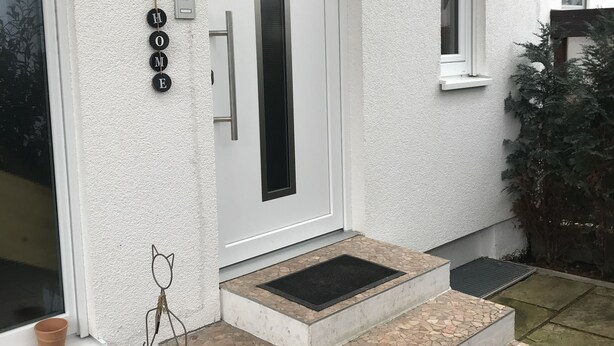 A white exterior with a door, a small window, and a mailbox. - Schön Apartments (Ohmden)