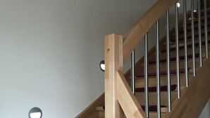 A wooden staircase with metal railings and purple carpeted steps. - Schön Apartments (Ohmden)